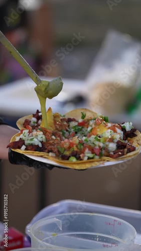 Vertical 9:16 slow motion macro close-up of green salsa verde poured over authentic al pastor tacos at a Southern California street taco stand, ideal for restaurant advertising, food marketing, and so