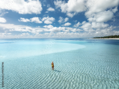 Canvastavla Aerial view of a woman in yellow bikini standing in shallow transparent turquoise water of Indian Ocean, Zanzibar island