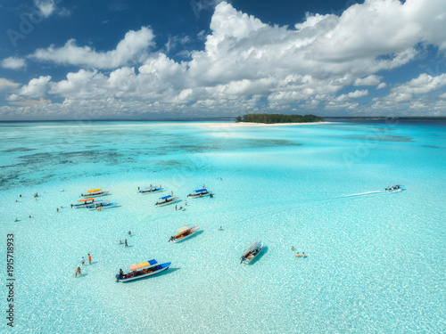 Φωτογραφία Aerial view of colorful boats in turquoise sea, blue sky with clouds near Mnemba Island, Zanzibar, Tanzania