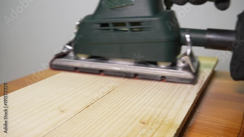 Orbital Sander Sanding Wooden Board Close Up in Workshop. Power tool sanding timber to create a clean, even finish
