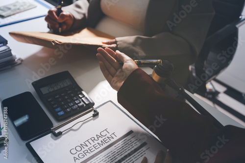Judge gavel with Justice lawyers having team meeting at law firm in background. Notary with client in office