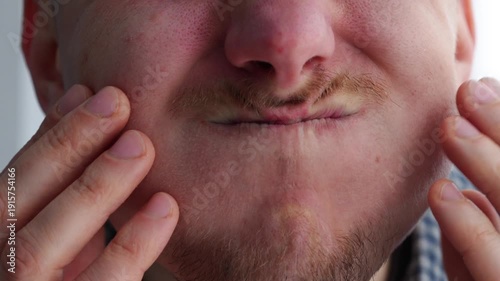A man puffs out his cheeks while holding his breath.
Air in the mouth.
Large cheeks on the face.