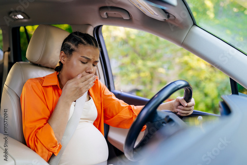 Foto Young black pregnant woman covering mouth while driving car, feeling nausea
