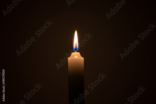 Candle burning brightly in a dark setting, representing hope and remembrance