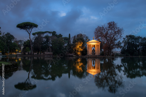 Panorama di alberi e tempio illuminato riflesso nel lago all'alba