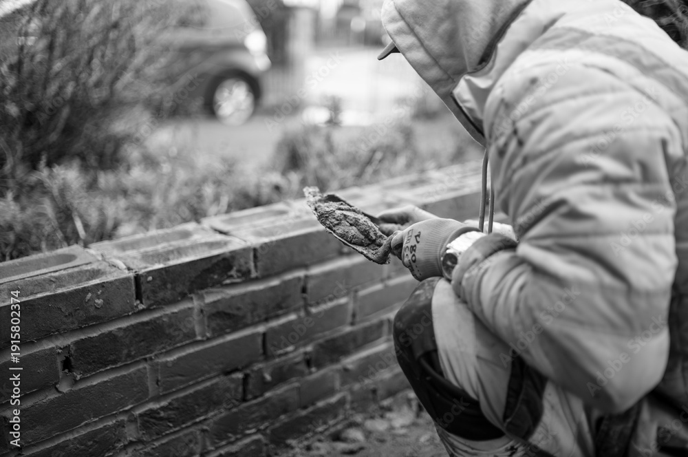 Fototapeta premium building works builders bricking a wall wearing hi vis black and white and colour 