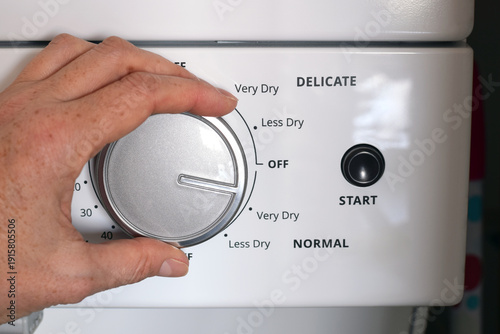 Quadro em tela Closeup person’s hand turning dial adjusting settings on household clothes dryer control panel