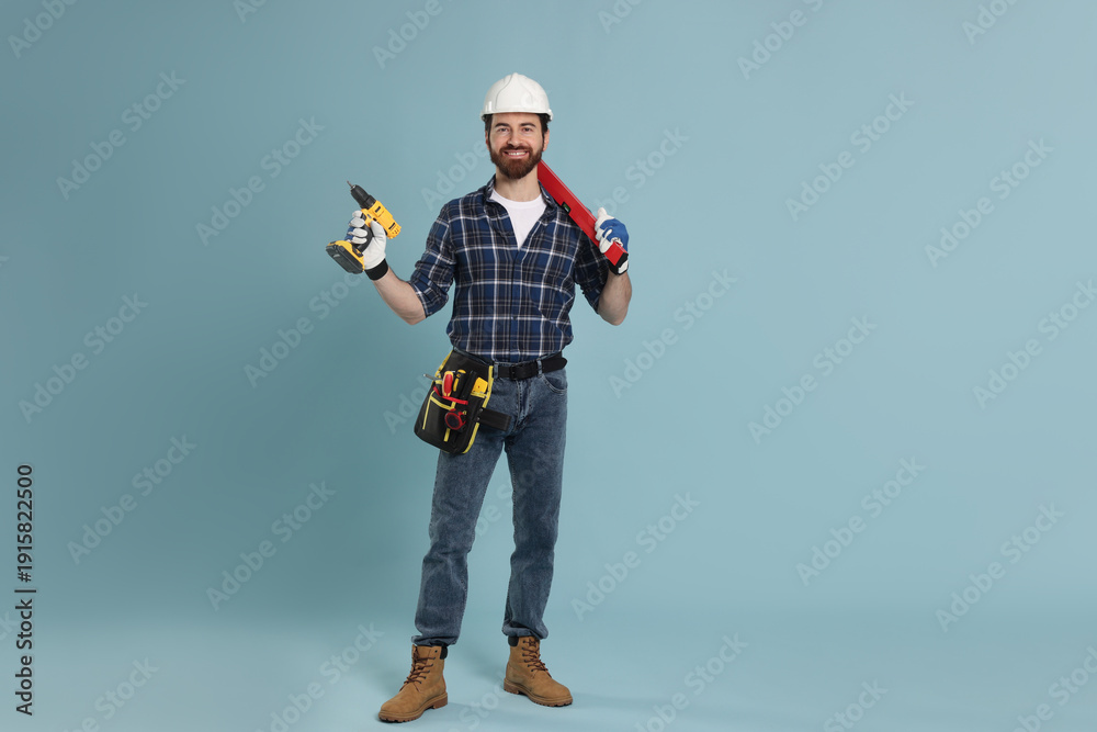Naklejka premium Professional builder with different tools on light blue background