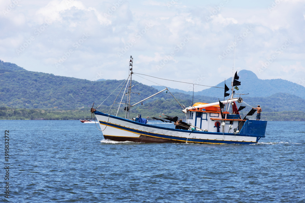 Obraz premium A fishing boat at sea photographed up close, mountains in the background