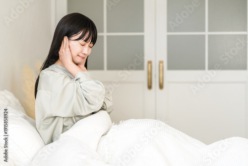 Photography A young Asian woman covering her ears from noise while sleeping in bed (noise tr