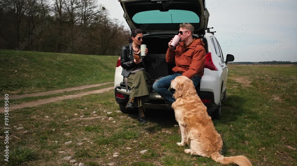 custom made wallpaper toronto digitalCouple sits at the back of a car with a golden retriever dog on the grass. They chat and eat snacks in a natural setting during the daytime.