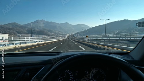 A video POV shot of a car driving on a highway through mountains on a clear day