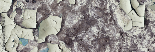 Peeling paint on the wall. Panorama of a concrete wall with old cracked flaking paint. Weathered rough painted surface with patterns of cracks and peeling. Wide panoramic texture for design background