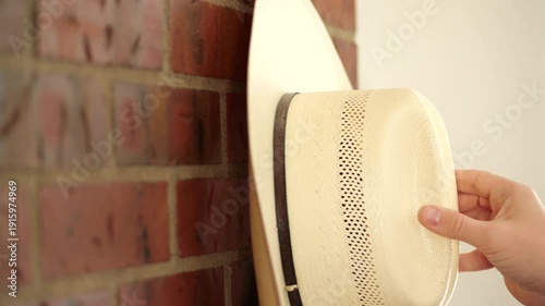 Person hanging cowboy hat on hook