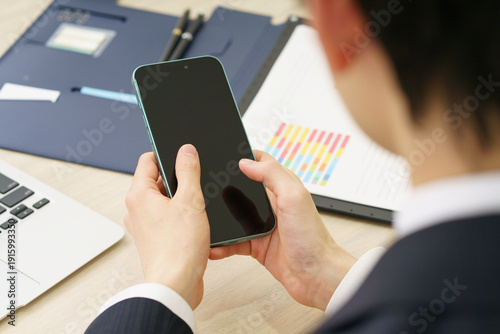 Photos スマホを手にする若い男性の手元のアップ