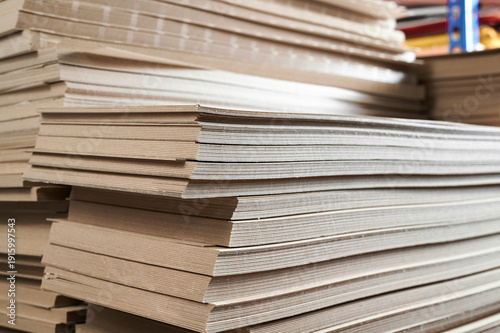 Foto Stacks of thick paperboard await transformation into durable cardboard boxes in