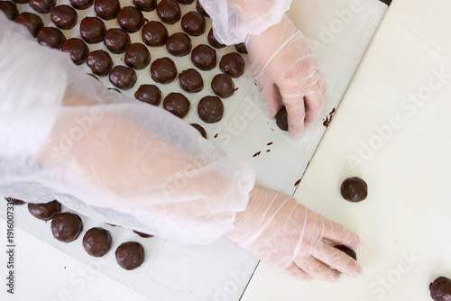 Фотография Manual arrangement of handmade chocolate candies by skilled hands in a confectio