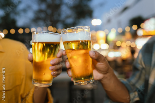 Foto Two people clinking glasses of cold beer at an outdoor night market, celebrating with street food and evening lights in the background