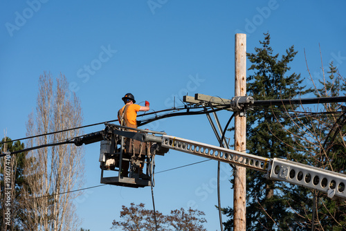 Foto Power utility lineman in an aerial lift bucket using a Cable Lasher to upgrade u