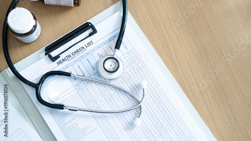 Fotografi Top view stethoscope on health checklist report on wooden table, concept of routine health examination, diagnostic screening and preventive medical care planning