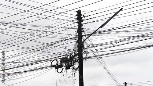 Urban Electrical Lines: A monochrome visual of a utility pole intricately laced with electrical wires against a cloudy sky, showcasing the complexity of urban infrastructure.