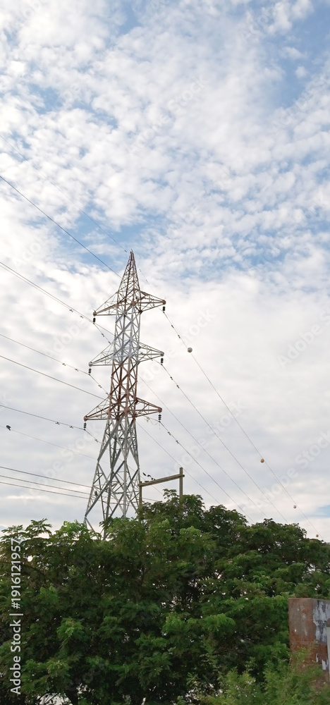 Obraz premium High Voltage Electricity Transmission Tower Under Cloudy Blue Sky