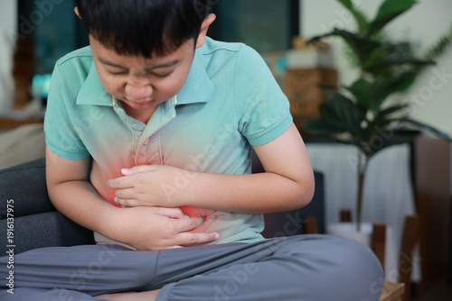 Bild auf Leinwand Asian boy holding belly suffering from severe abdominal pain with red inflamed area