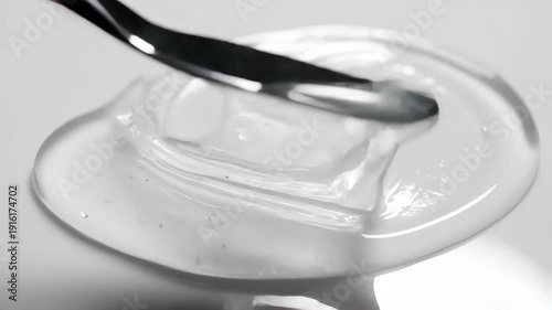 Macro shot of clear cosmetic gel being spread with a metal spatula. Texture of transparent skincare serum. Beauty product application concept