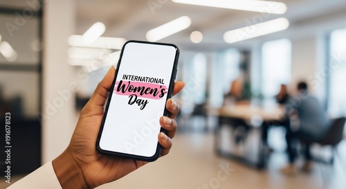 Commemorating International Women's Day A hand holding a smartphone with a heartfelt message in a bright office