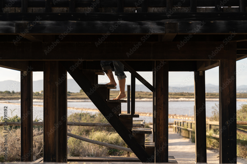 Obraz premium Barefoot person climbing wooden stairs overlooking salt pans