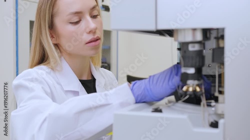 Woman preparing high performance liquid chromatography system with sample vials. Chemical analysis, biotech research and laboratory workflow theme.