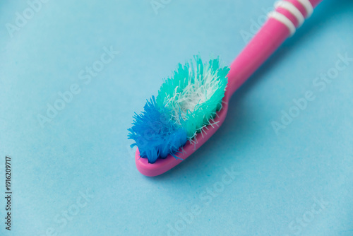 Concept of proper teeth brushing and oral care. Old used toothbrush close-up on a blue background