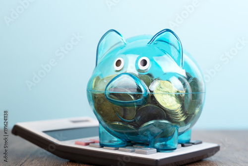 Transparent piggy bank on top of calculator business and financial concept