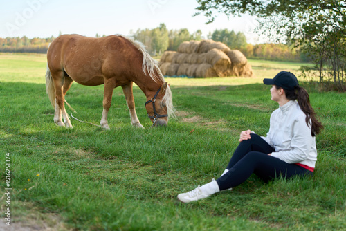 Photography Equestrian lady stroking a young horse outdoors