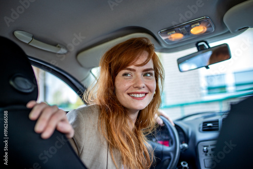 Foto Female driver looking back while reversing a car in a city environment