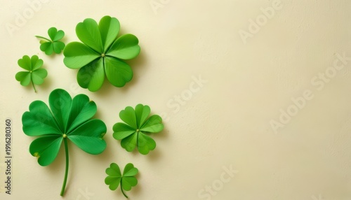 St. Patrick's Day background with green shamrocks and clovers on a cream-colored surface, flat lay with copy space.