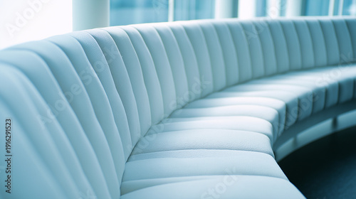contrapositive. A minimalist, flowing arc of upholstered seating on a blurred neutral background. real-estate listings.