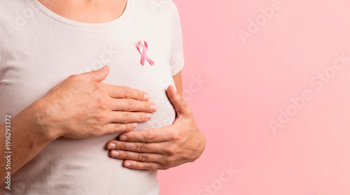 Wallpaper Mural Close-up of a young woman doing a breast self-exam on a pink background - concept of breast cancer awareness, early detection and women's health. Torontodigital.ca