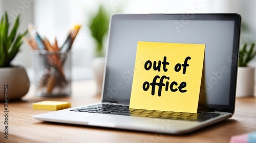 Yellow sticky note with 'out of office' message attached to a laptop screen