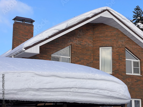 Heavy snow accumulating on residential brick house roof