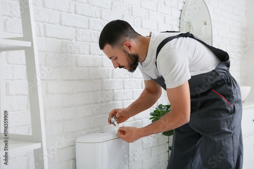 Male plumber repairing toil...