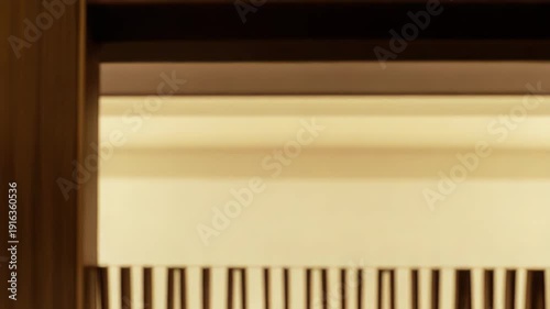 Interior architectural detail of warm golden vertical wooden slats forming an elegant decorative divider with a reflective base, emphasizing modern lines, texture and luxurious minimalist ambiance