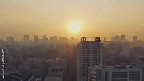 Urban panoramic view of a city silhouette with numerous skyscrapers and office buildings at sunset, creating a hazy atmosphere with visible air pollution and smog over the metropolis