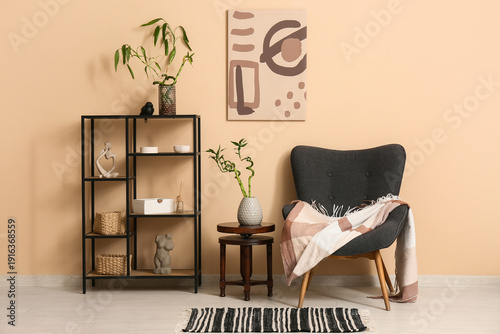 Stylish armchair, shelving unit with decor and bamboo stems near color wall