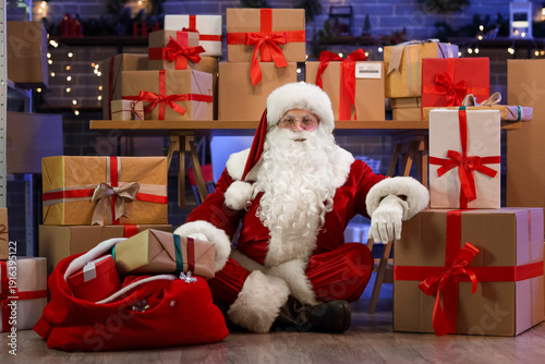 Santa Claus with many gift boxes and bag in post office
