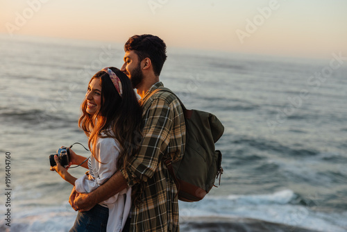 Tableau sur toile The light we found: A couple watching the sun set over the ocean