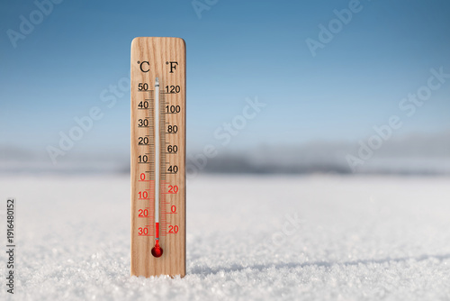 White celsius and fahrenheit scale thermometer in snow. Ambient temperature minus 23 degrees celsius