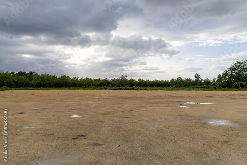 Tableau sur toile Vast barren field under brooding sky: expansive rural landscape with textured ea