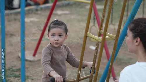 slow motion of cheerful child girl playing on double swing with her mother at outdoor playground