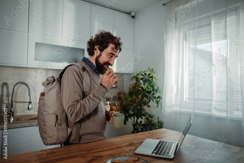 Fotografi Man snacking and working from home in kitchen